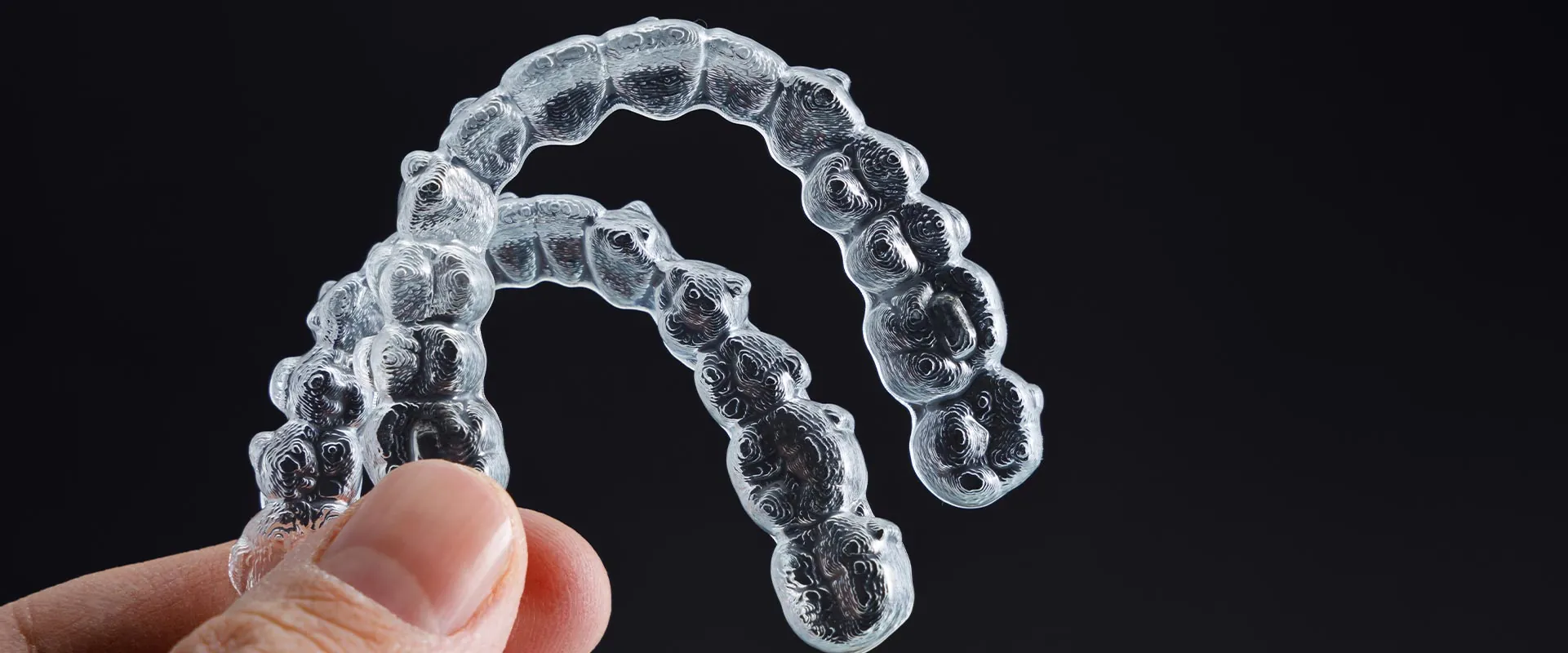 person holding up a pair of Invisalign clear aligners