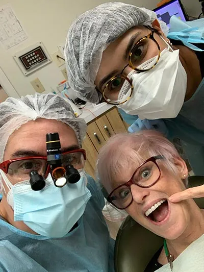 Dentist and staff with preventive dentistry patient smiling and pointing to tooth